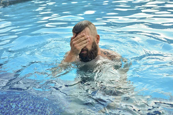 髭を生やした男がプールで泳いでいる プールに髭を生やした男 休暇でブルネットの男 夏休みのコンセプト — ストック写真