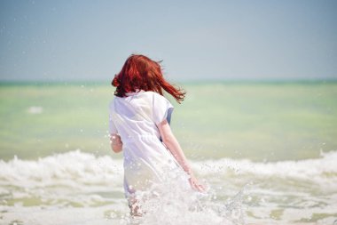 Denizde bir kız. Genç kızın portresi. Gençler için yaz tatili kumları. Güneşli bir gün ve deniz. Çocukluk tatili. Sahilde sarı mayolu bir genç..