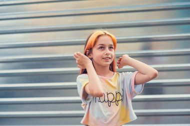 İtaatkar kız portresi. Gündüz vakti dışarıda bir çocuk. Okul çağında şık saç boyalı güzel bir kız. Pozitif portre. Kakülleri boyalı kurnaz bir kız. Kız 9-11 yaşında.