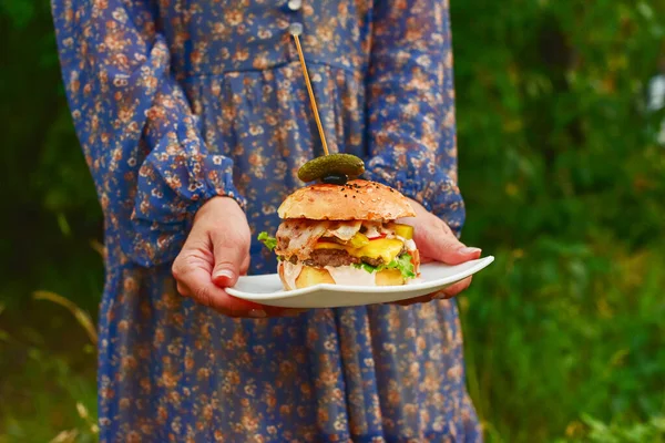 Juicy burger. A burger in the hands of a woman. Breakfast concept, Shopkeeper\'s market photo, Delicious food concept, Fast food concept, Food and drink. Hand holding a tasty fast food cheeseburger.