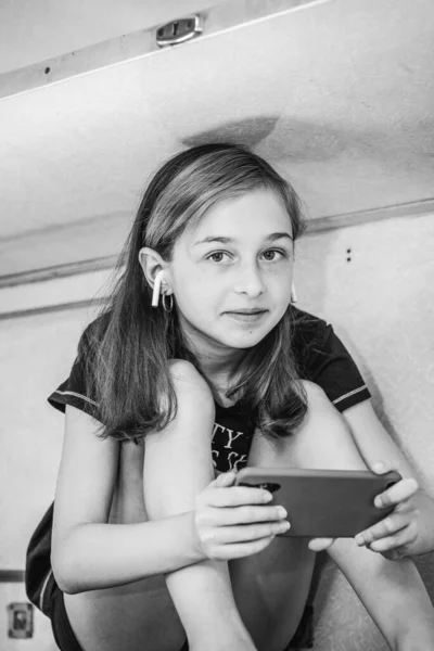 電車で旅をしながらスマホを使っている女の子 電車の中の女の子はスマートフォンを見ている ティーネージャーガジェット休暇旅行コンセプト — ストック写真