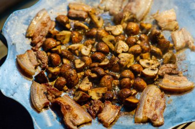 Kızarmış mantar ve pastırma ormanda ateşte bir tavada. Doğada yiyecek. Yolda yemek pişirmek. Piknik. Tavada mantar ve pastırma.