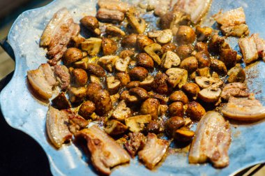 Kızarmış mantar ve pastırma ormanda ateşte bir tavada. Doğada yiyecek. Yolda yemek pişirmek. Piknik. Tavada mantar ve pastırma.