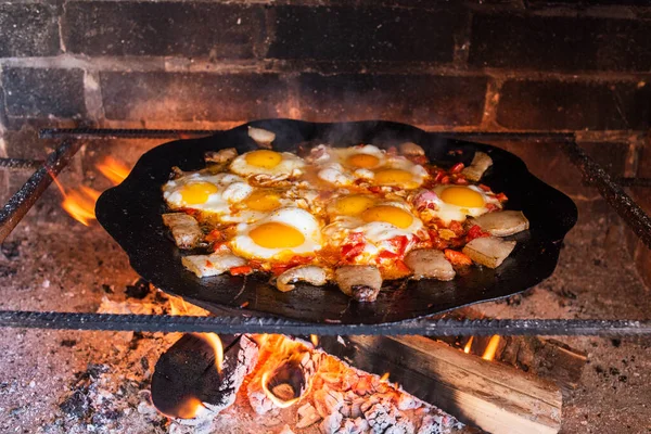 Eggs are fried on a fire in the street. Fried eggs with bacon. A dish of many fried eggs on a bonfire in the oven. Street food. Rest with food. Grilled eggs in a pan