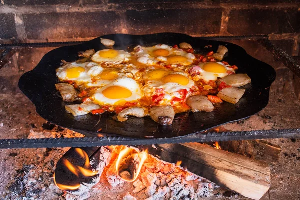 Eggs are fried on a fire in the street. Fried eggs with bacon. A dish of many fried eggs on a bonfire in the oven. Street food. Rest with food. Grilled eggs in a pan