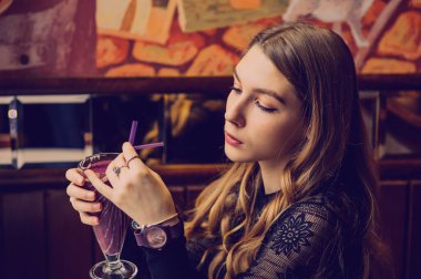 Meyveli buzlu güzel genç bayan. Kafede smoothie içen bir kız. Siyah elbiseli kız. Doğal saçlı bir kız. Kız ve kafede rahatlama, sağlıklı yiyecekler, vitaminler. Sakin kavram