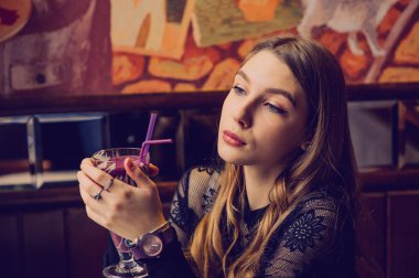 Meyveli buzlu güzel genç bayan. Kafede smoothie içen bir kız. Siyah elbiseli kız. Doğal saçlı bir kız. Kız ve kafede rahatlama, sağlıklı yiyecekler, vitaminler. Sakin kavram