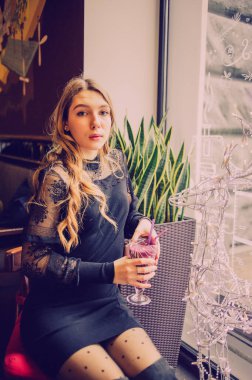 Meyveli buzlu güzel genç bayan. Kafede smoothie içen bir kız. Siyah elbiseli kız. Doğal saçlı bir kız. Kız ve kafede rahatlama, sağlıklı yiyecekler, vitaminler. Sakin kavram