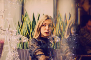 Meyveli buzlu güzel genç bayan. Kafede smoothie içen bir kız. Siyah elbiseli kız. Doğal saçlı bir kız. Kız ve kafede rahatlama, sağlıklı yiyecekler, vitaminler. Sakin kavram