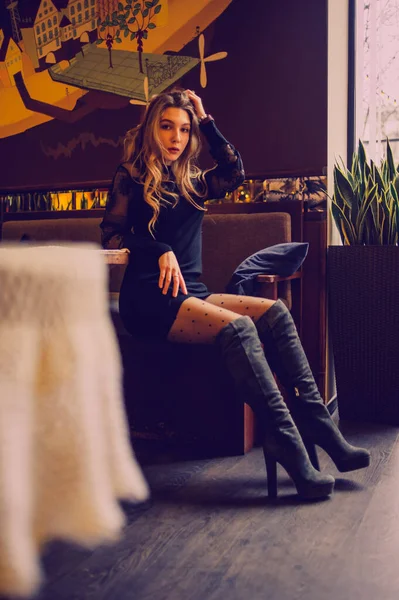 Portrait of a girl. Elegant lady in a black dress in a restaurant alone. Girl in a cafe. Pensive mood of a beautiful girl. Bold young girl with silky hair. People, fashion, lifestyle and color concept