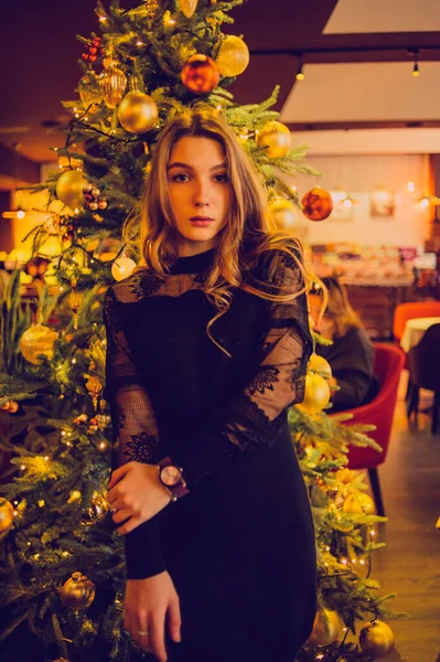 Portrait of a girl. Elegant lady in a black dress in a restaurant alone. Girl in a cafe. Pensive mood of a beautiful girl. Bold young girl with silky hair. People, fashion, lifestyle and color concept