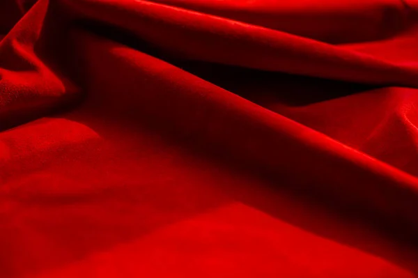 Dark red matte background of suede fabric, closeup. Velvet texture of seamless wine leather. Felt material macro. Red texture