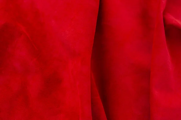 Red matte background of suede fabric, closeup. Velvet texture of seamless wine leather. Felt material macro. Red texture