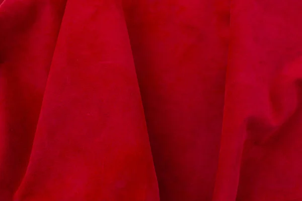 Red matte background of suede fabric, closeup. Velvet texture of seamless wine leather. Felt material macro. Red texture