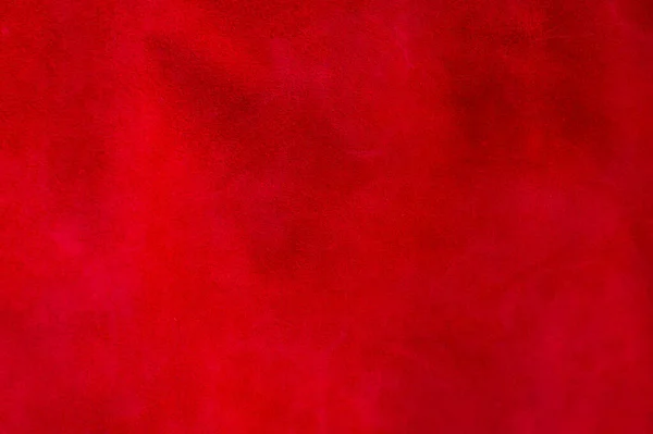 Red matte background of suede fabric, closeup. Velvet texture of seamless wine leather. Felt material macro. Red texture