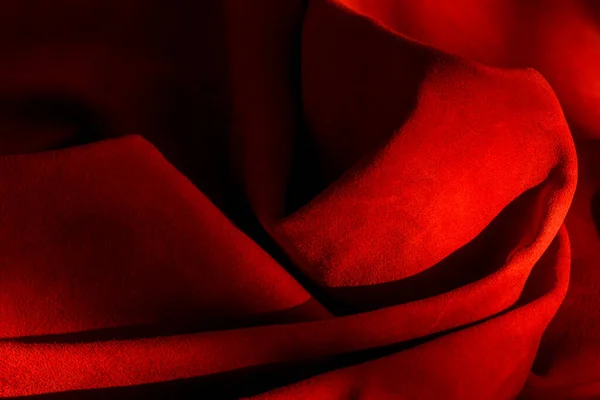 Dark red matte background of suede fabric, closeup. Velvet texture of seamless wine leather. Felt material macro. Red texture