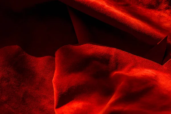 Dark red matte background of suede fabric, closeup. Velvet texture of seamless wine leather. Felt material macro. Red texture
