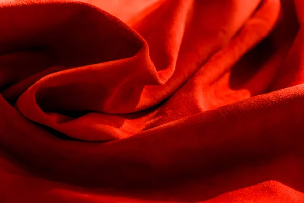 Dark red matte background of suede fabric, closeup. Velvet texture of seamless wine leather. Felt material macro. Red texture