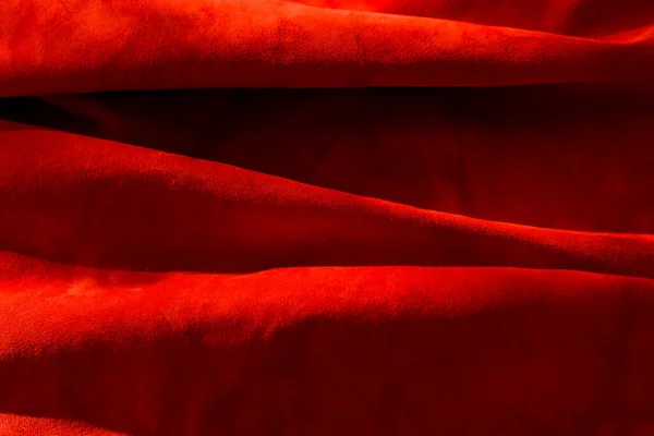 Dark red matte background of suede fabric, closeup. Velvet texture of seamless wine leather. Felt material macro. Red texture