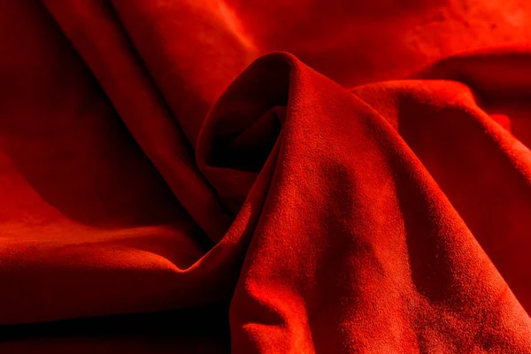 Dark red matte background of suede fabric, closeup. Velvet texture of seamless wine leather. Felt material macro. Red texture