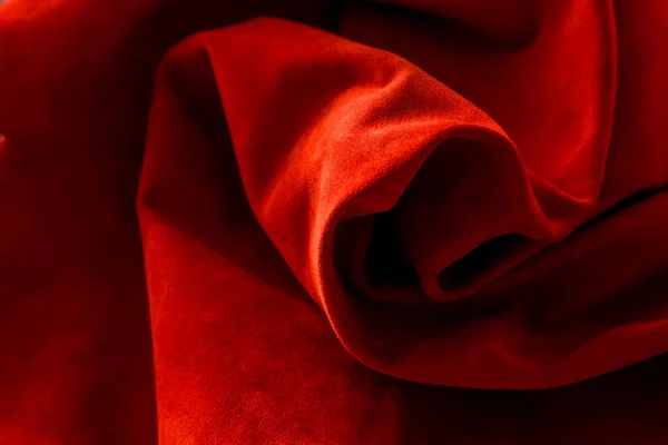 Dark red matte background of suede fabric, closeup. Velvet texture of seamless wine leather. Felt material macro. Red texture