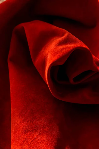 Dark red matte background of suede fabric, closeup. Velvet texture of seamless wine leather. Felt material macro. Red texture