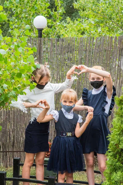 Three schoolgirls wearing masks and going back to school during covid-19 pandemic. Three schoolgirls wearing protective masks. Virus, bacteria, school, protection. Teen girls in school uniform