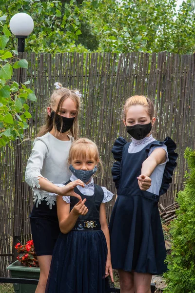 Three schoolgirls wearing masks and going back to school during covid-19 pandemic. Three schoolgirls wearing protective masks. Virus, bacteria, school, protection. Teen girls in school uniform