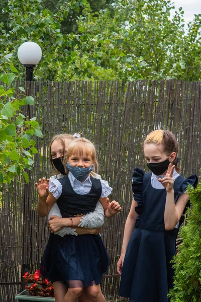 Three schoolgirls wearing masks and going back to school during covid-19 pandemic. Three schoolgirls wearing protective masks. Virus, bacteria, school, protection. Teen girls in school uniform