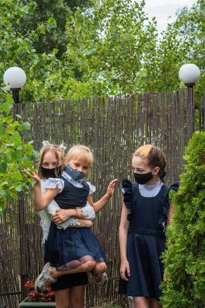 Three schoolgirls wearing masks and going back to school during covid-19 pandemic. Three schoolgirls wearing protective masks. Virus, bacteria, school, protection. Teen girls in school uniform