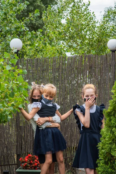 Three schoolgirls wearing masks and going back to school during covid-19 pandemic. Three schoolgirls wearing protective masks. Virus, bacteria, school, protection. Teen girls in school uniform