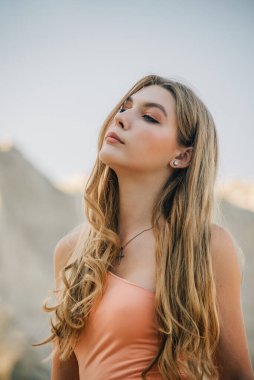 Kumların arkasındaki kız. Bir kızın portresi. Yazın uzun sarı saçlı genç bir kız.