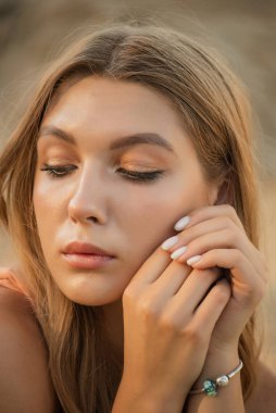 Kumların arkasındaki kız. Bir kızın portresi. Yazın uzun sarı saçlı genç bir kız.