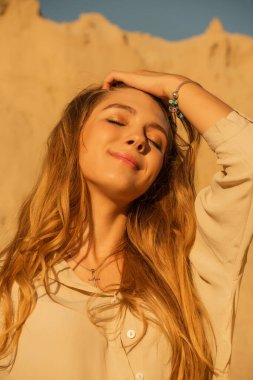 Kumların arkasındaki kız. Bir kızın portresi. Yazın uzun sarı saçlı genç bir kız.