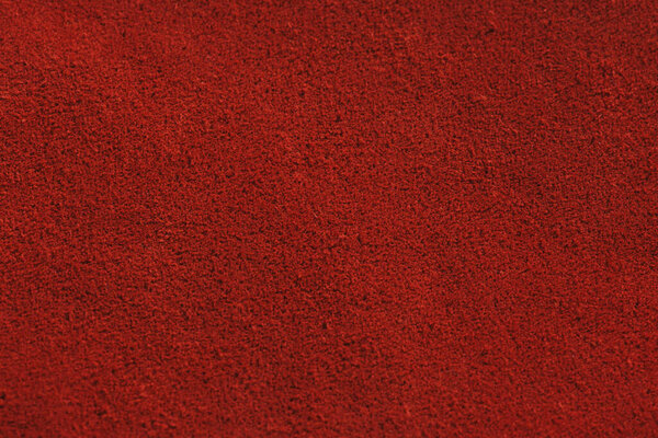 Red matte background of suede fabric, closeup. Velvet texture of seamless leather. Felt material macro. Red suede texture. Fabric, leather, material for designers.
