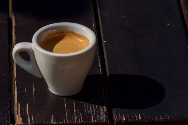 木製のテーブルの上にコーヒーマグカップ アラビカ産のホットエスプレッソコーヒーのカップが食感を背景に 木製テーブルの上の白いセラミックカップのブラックコーヒー — ストック写真