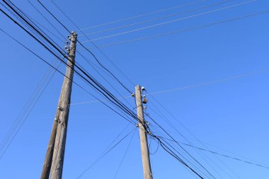 Mavi gökyüzüne karşı telleri ile elektrik direği