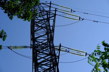 Mavi gökyüzüne karşı telleri ile elektrik direği