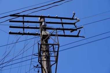 Mavi gökyüzüne karşı telleri ile elektrik direği