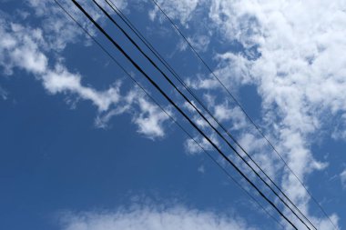 Mavi gökyüzüne karşı telleri ile elektrik direği