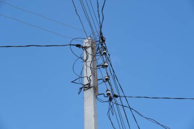 Mavi gökyüzüne karşı telleri ile elektrik direği
