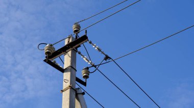 Mavi gökyüzüne karşı telleri ile elektrik direği