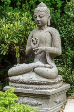 Garden sculpture of a young sitting buddha meditating clipart