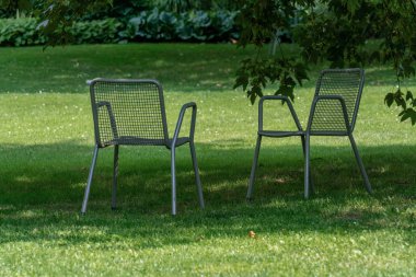 Gölgede bir hugh ağacının altında bir parkta iki sandalye