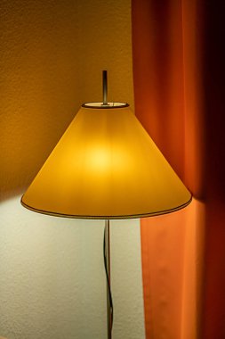Sarı bir gölge ve ba turuncu bir perde ile parlayan lamba