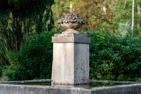 Monumento de piedra con una cesta llena de flores como parte de un agua — Foto de Stock