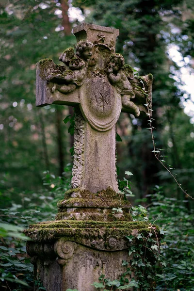 Stone cross tombstone decorated with two cherubs and covered wit — Zdjęcie stockowe