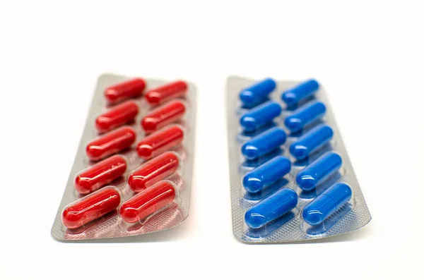 Червоні та сині таблетки в блістерній упаковці ізольовані на білому тлі — стокове фото