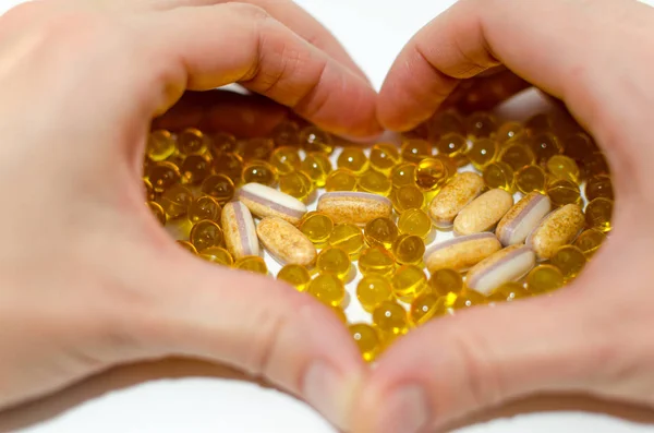 Vitamins. Womans hands created a heart shape.White and yellow pills.Mock up for special offers as advertising.Medical and healthcare concept.Copy space.