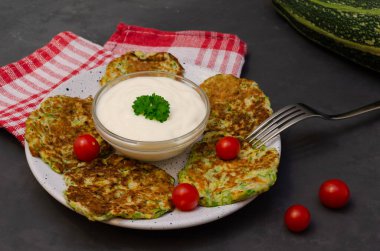 Yoğurt ve maydanozla servis edilen sebzeli kabaklı börek. Arka planda yemek pişirmek için gerekli malzemeler. Sağlıklı beslenme. Seçici odak.